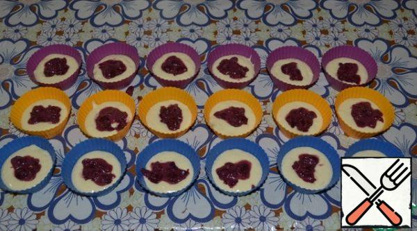 Put 2/3 of the dough on greased mini cupcake molds. The forms must be filled in half. If the molds are silicone, then you do not need to lubricate them. Spread the cherry-chocolate filling on top.
