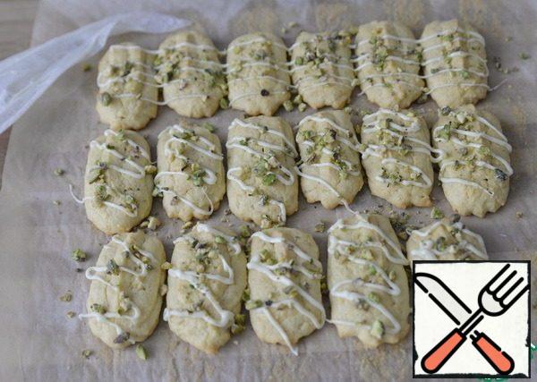 In the culinary package put the broken white chocolate. Heat the pulses for 20-30 seconds until the chocolate melts. Cut off the tip of the package. Put the picture on the cookie. Top immediately (not yet frozen chocolate) sprinkle crumbs of pistachio.