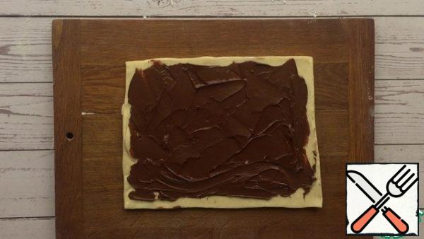 Next, cut from the same puff pastry rectangle and smear it whole nut-chocolate paste, leaving each edge of 0.5 cm.