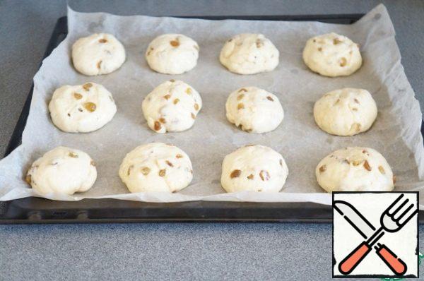 Not knead put the dough on the table. Divide in half, then again in half. And cut each part into three. Thus, you will get 12 approximately identical pieces. Roll each ball, put on a baking sheet. Cover with a towel and leave for 40 minutes.