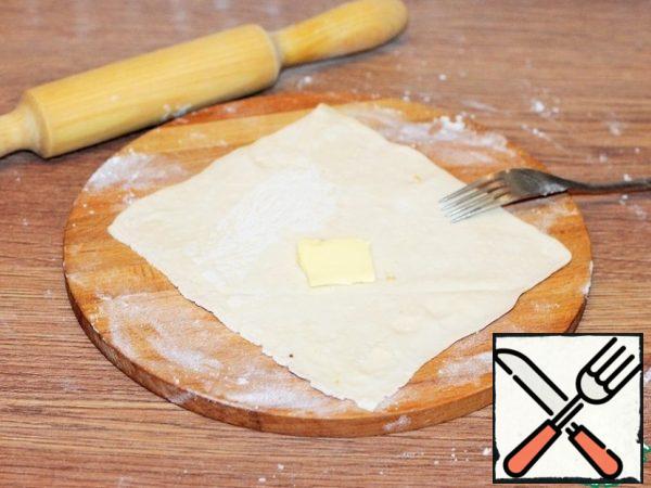 Six parts of the dough roll out into the formation and increase in size by 1.5-2 times. Pierce the dough with a fork and put a small piece of butter.