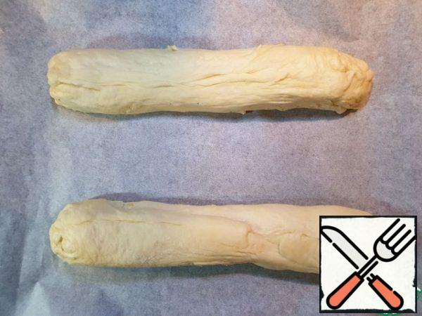 Cut the resulting roll into 2 parts. We form loaves with our hands, slightly pulling the dough.
