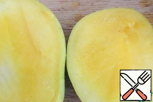 While the biscuit is baking, prepare the cream.
Mango cut into two parts, so that the bone remained in the middle.