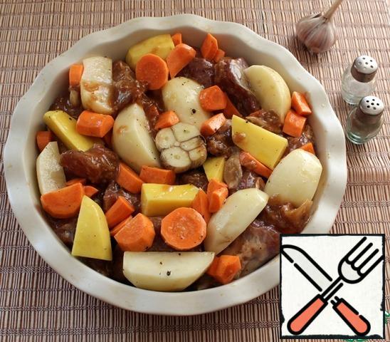 In a baking dish put the meat and vegetables. A head of garlic cut in half, put on the vegetables. It is advisable to add 2-3 sprigs of rosemary and juniper berries.