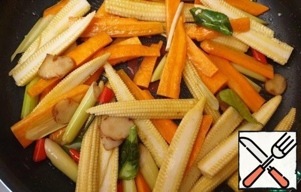 Cut corn in half, carrots into strips. Fry the carrots for a couple of minutes, add the corn. Fry for a couple of minutes.