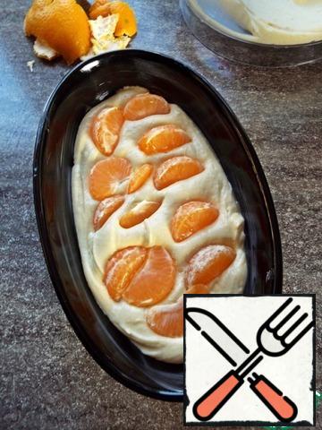 Grease the form with butter. Put half of the dough.
Arrange the tangerine slices on top.