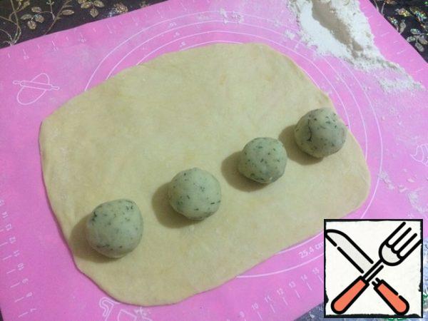 Take one piece of dough, roll out into a rectangle and spread with one edge 4 balls of potatoes.