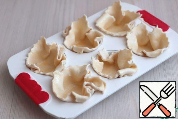 Place the squares of puff pastry in a capsule form for baking muffins.
