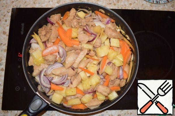 Fry the chicken fillet for 5 minutes. Add carrots, onions and pineapple pulp, simmer for 7-10 minutes.
Lay out half of the pineapple, garnish with chopped herbs.
