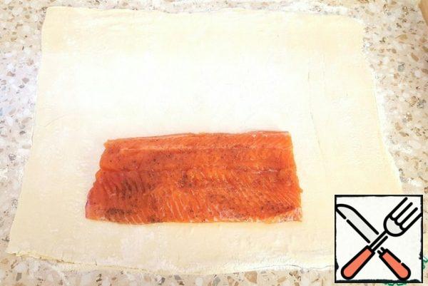 Roll out the dough (lightly).
Season the fillets with salt and pepper on both sides.
Put half of the fish on the dough.
