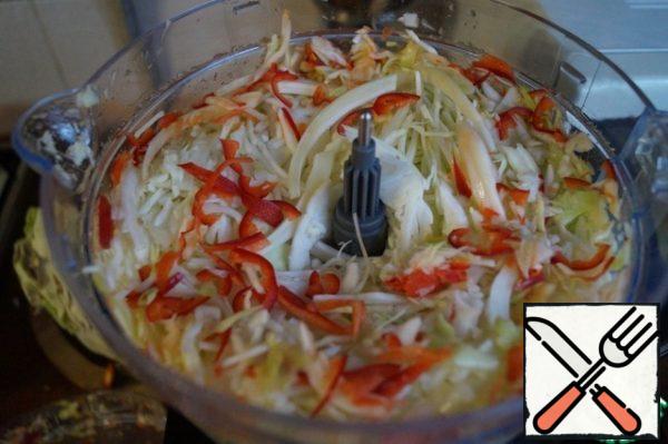 Cabbage with the help of a combine, chop into strips along with carrots and bell peppers.