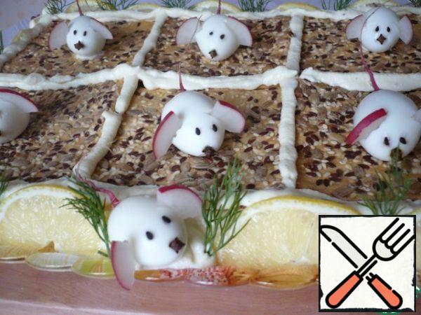 After impregnation, decorate the cake as desired. The opportunity to fantasize with the design of this cake will delight lovers of a beautiful dish. Brush the edges of the cake with the remaining cream and garnish with sliced lemon slices and dill sprigs. (I decorated the top of the snack cake with quail egg mice, radish ears, sesame eyes, and a clove nose.)
