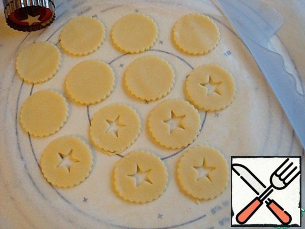Roll out the dough with a rolling pin in a layer 3 mm thick. Cut out cookies of any shape. In half of them, make a hole in the center.
