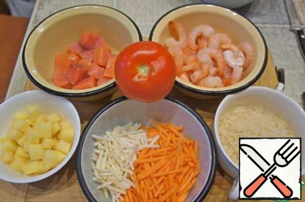 Prepare the products. Cut the fish into cubes, defrost the shrimp. Wash and peel the vegetables. Cut the potatoes into small cubes, chop the carrots and celery into strips. Rinse the rice thoroughly.
