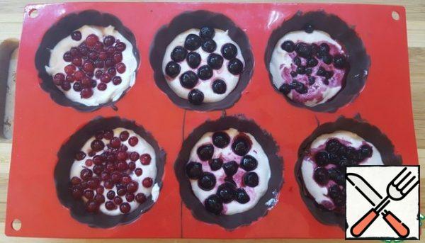 Fill the molds with a third of the curd mass, put the berries on top.
