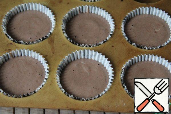 Put the paper cupcake capsules in a mold, pour the dough, not reaching the edge by about 5 mm.
