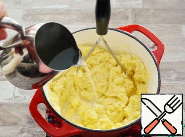 Adding gradually the potato broth, knead and mix the mashed potatoes with a potato masher to the desired consistency.
