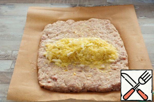 Spread the minced meat on a sheet of parchment, put the filling in the center. Press it down slightly with your hands.
