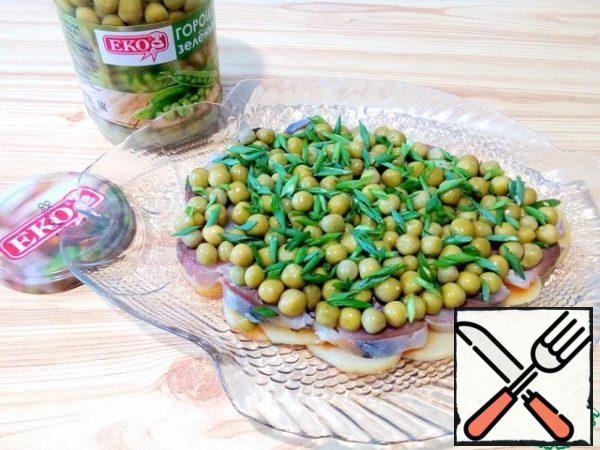 On the herring lay green peas. Cut the green onions and arrange on the green peas.