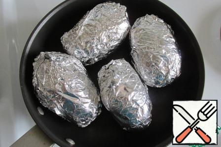 Each potato is wrapped in foil and placed in a form.
Put in the oven, turn it on and set the temperature to 200 degrees., bake the potatoes for 1 hour. Readiness can be checked with a thin knife directly through the foil.