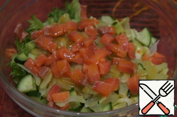Cut off a few thin strips of salmon for decoration, cut the rest into small cubes and add to the salad. Gently mix the mixture.