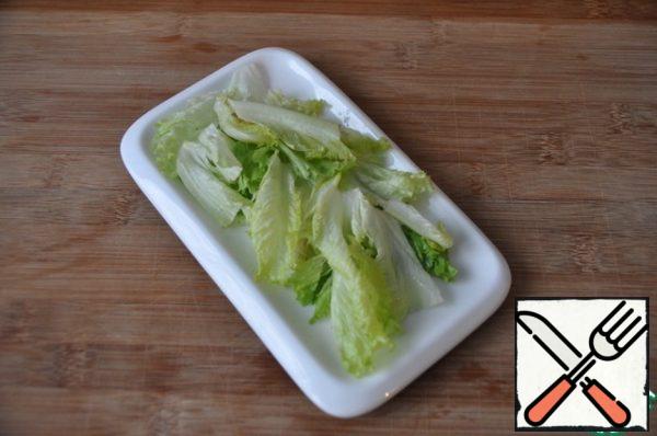 Take the lettuce leaves, wash, dry with a towel, tear or cut, put on a serving plate.