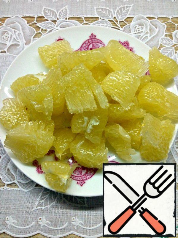 Clean the pomelo from the skin and film, divide each slice into 3-4 parts.