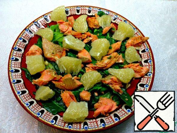 Put the fish on top of the spinach, along with the marinade and pieces of pomelo. Sprinkle with sesame seeds.