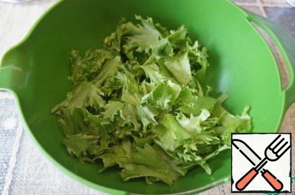 For salad, it is better to take crispy varieties (cheese, frieze, iceberg).
Cut the lettuce leaves into pieces with your hands.
