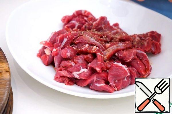 Cut the beef into thin slices 0.5 cm thick, pepper and marinate the meat in a spoonful of soy sauce.