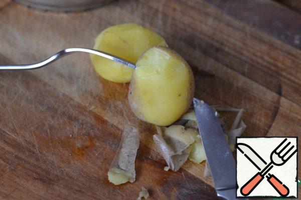 Wash the potatoes and boil them in their skins.
Peel them while still hot. Help yourself with a fork by pinning hot potatoes on it.