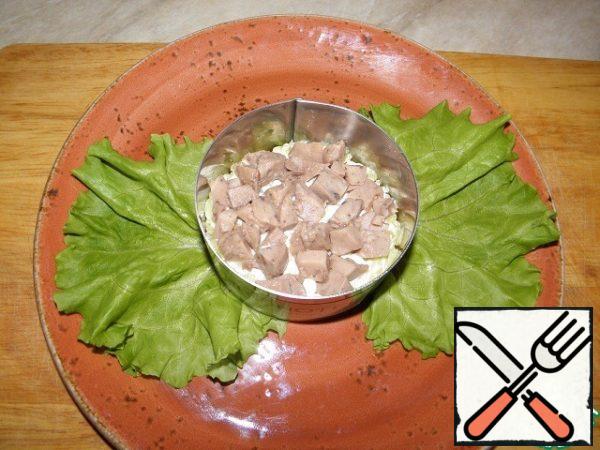 Next, open the jar with cod liver, drain the oil, cut the liver into small pieces and spread on potatoes.
