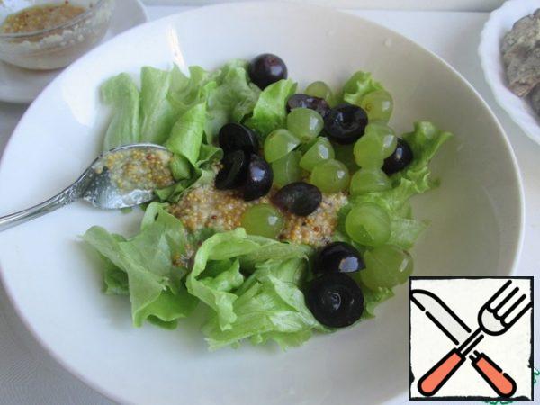 Tear salad leaves with your hands. (You can take any lettuce leaf, or use a mix of several types).
Cut the grapes in half. If there are bones, then remove them.Combine the salad leaves with the grapes, add the sauce, stir and put on the liver.
Optionally, you can add tomatoes.
