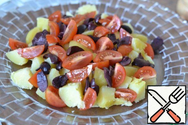 Top the potatoes with sliced cherry tomatoes and sliced olives.