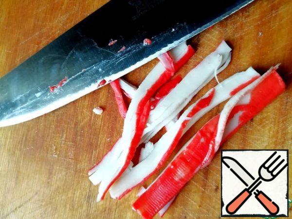 Crab sticks as thinly as possible and along the fibers cut into strips. I insist in this recipe on a neat and thin cut, it will give the airiness of the salad.