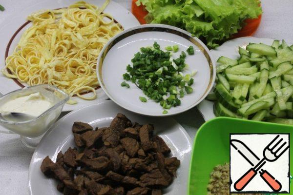 Cut the beef into small cubes, fry in a pan until tender and tender, adding water during cooking. Add the crushed garlic to the mayonnaise and mix. Wash the lettuce leaves, cut the onion, cut the cucumbers into strips, cut the pancakes into rings, and chop the walnuts.