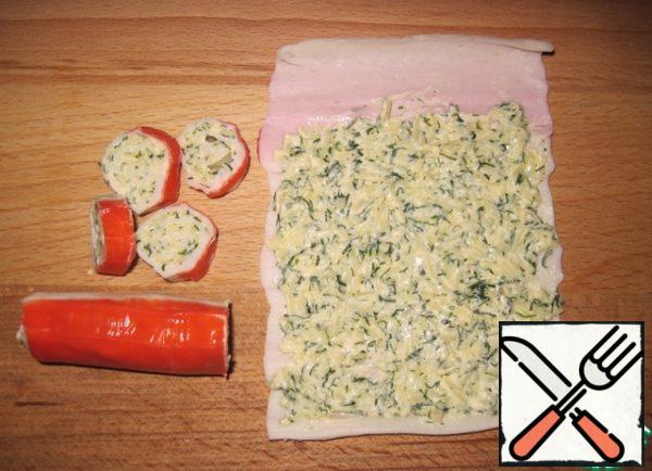 Grate the cheese on a large grater, mix half of the cheese with 1 tbsp of mayonnaise and dill. Two crab sticks are carefully deployed, put an even thin layer of filling and roll into a roll.