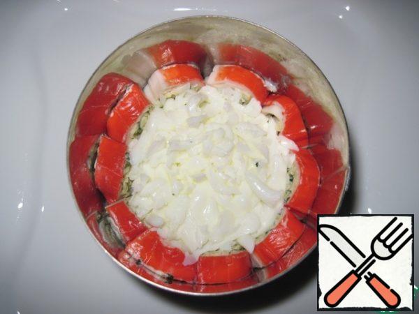 The crab stick rolls are carefully thinly sliced and distributed inside the cooking ring. Grate the egg white on a large grater, put the first layer of salad on the bottom of the cooking ring.