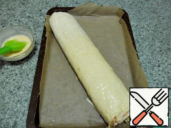 Then transfer to a baking sheet, unfolding the paper under the roll, cut off the excess with scissors.
Mix the egg with two tablespoons of milk.
Lubricate the roll liberally, sprinkle with sesame seeds or flax.
We send it to a preheated 180 ° C oven, bake until golden brown.
All the products used in the roll are ready, except zucchini. 30 minutes is enough to bake them.
Remember that we all have different stoves - electric, gas, large, small. Once in the recipe, as a guide, you look at your cooking technique.
Leave the finished rolls to cool.
It is not necessary to cut it hot, because the cheese is not frozen yet.
