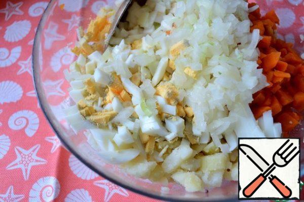 Cut the onion in advance, pour boiling water, drain the water after a couple of minutes, rinse with cold water and let it drain. Put it in a salad bowl.
Chop the eggs and add them.