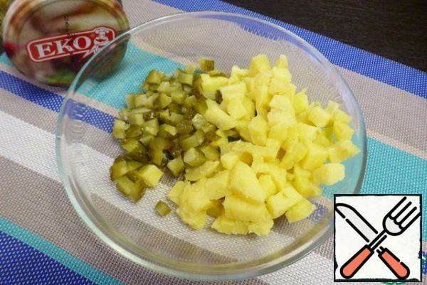 Dice the boiled potatoes and pickles. Fold the slicing into a bowl.