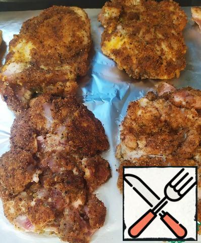 Next, cover the baking sheet with foil and put the fried pieces of chicken thigh fillet.