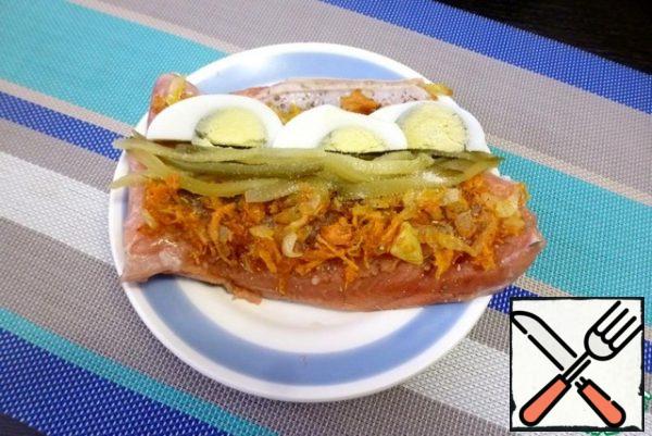 On the thin side of the fillet (where the abdomen is), put the pickled cucumber straws and quarters of eggs. Sprinkle the entire surface with gelatin.

