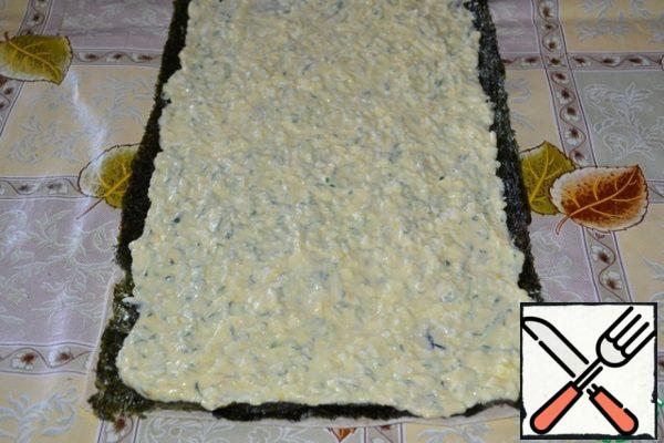 Carefully put the cooked egg-cheese mass on top of the nori, not reaching the edge of 1 cm, level it out.
