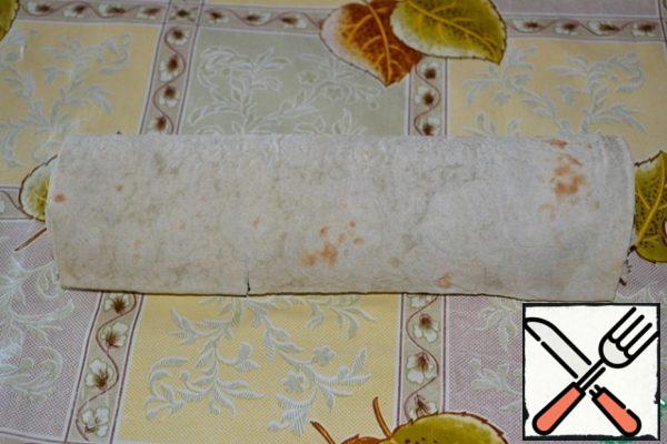 Carefully roll into a roll. Wrap it in plastic wrap and put it in the refrigerator for 2-3 hours for cooling and impregnation.