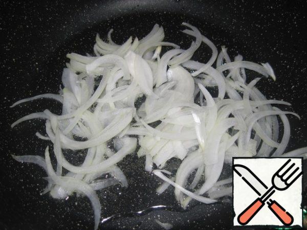 In a pan with preheated vegetable oil, fry the onion, cut into thin half-rings, on medium heat for 2-3 minutes.