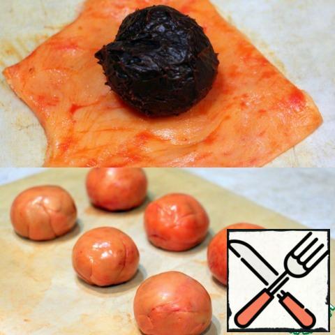 In advance get from refrigerator orange mass of, to she warmed up. Tear off the pieces of the mass, roll it out a little on a silicone Mat, but not thinly, otherwise the truffle will Shine through or break when forming (which I have happened with one of the truffles). In the middle, put the truffle, and connect the edges, gently smoothing the folds, forming tangerines.