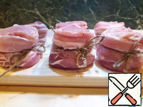 Slice tenderloin across the grain with a thickness of 5-6 cm.
Wrap a strip of bacon.
Tie with cooking thread or twine to preserve the shape of the medallions.