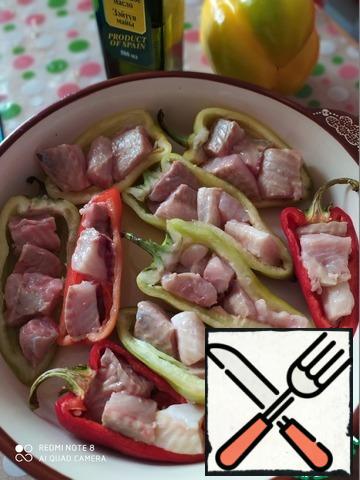 In the form in which you will bake peppers-pour half the norm of olive oil, place the peppers, cut in half and cleaned. Cut the fish into pieces-fill the peppers.