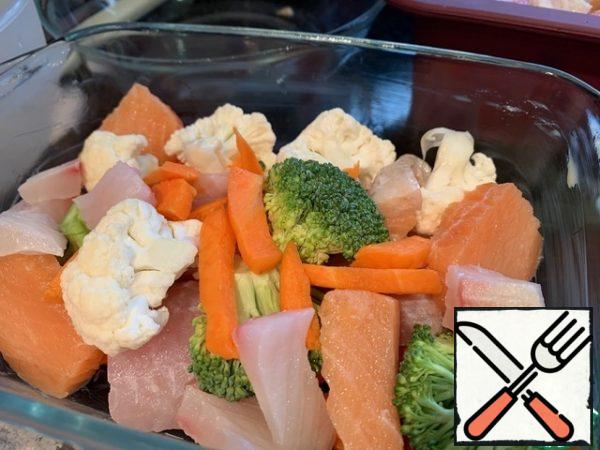 In a baking dish, alternately put the cauliflower, broccoli, carrots and fish.